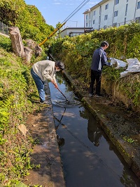 溝を掃除する学生
