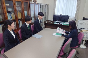 久保理事に冊子を紹介する学生