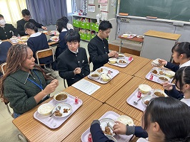 留学生と机を並べて給食を食べる中学生たち
